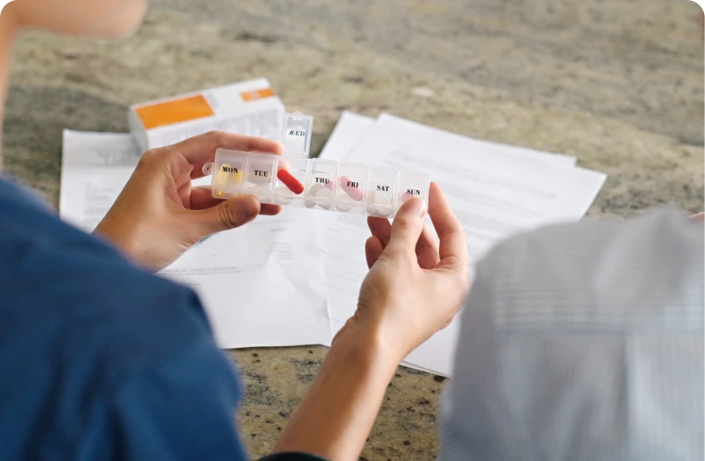 Hands organizing weekly pill container